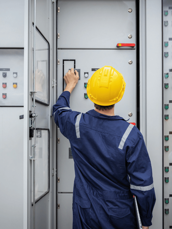 Electrician in a hard hat working on a commercial electrical switchgear panel